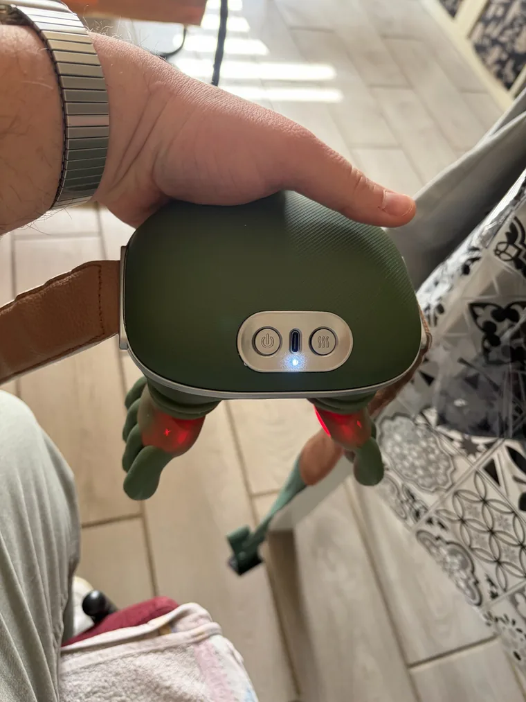 Le châle de massage Nuquea tenu en main, allumé, les diodes rouges de chauffe visibles sous les têtes de massage